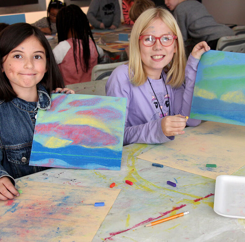 Two children showing artwork they made on a school field trip