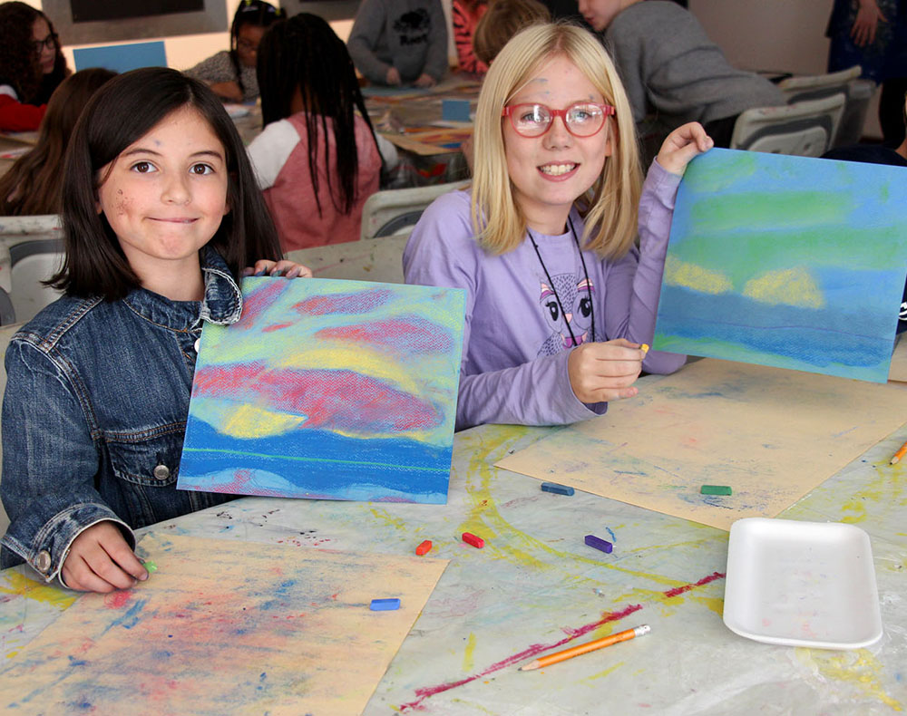 Two children showing artwork they made on a school field trip